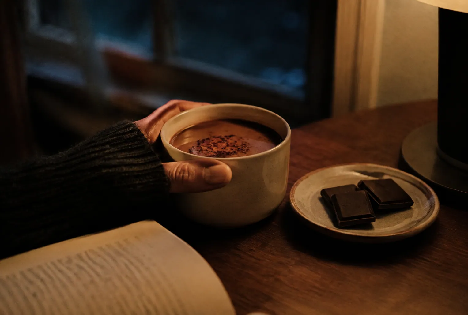 夜の小さな食卓で、チリを浮かべたホットチョコレートを両手で包む