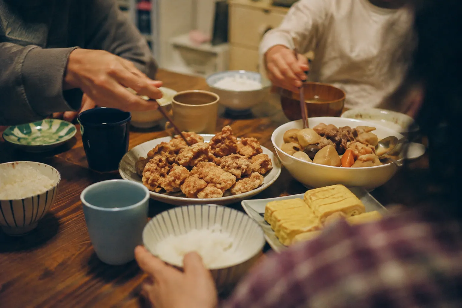 唐揚げや煮物を囲む普段の家族の食卓