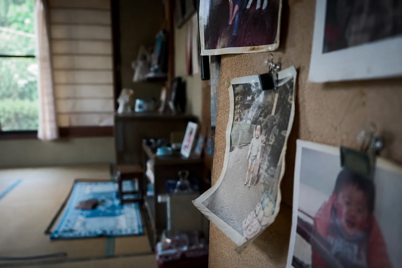 畳の部屋で壁に留められた色褪せた家族写真